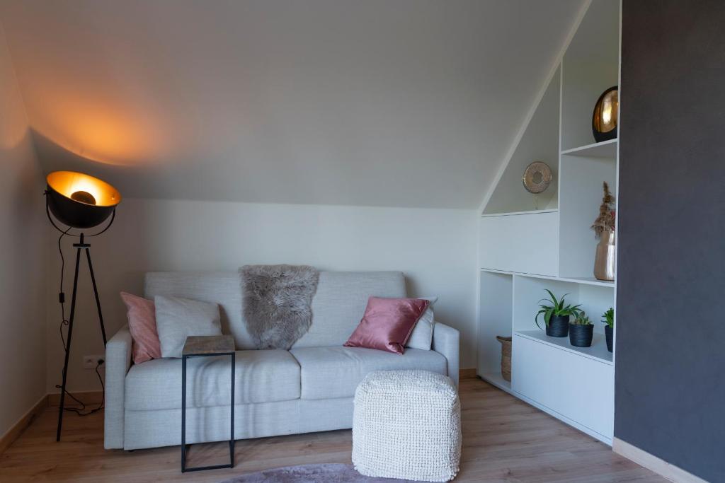 a living room with a white couch with pink pillows at De Weldoeninge in Wingene