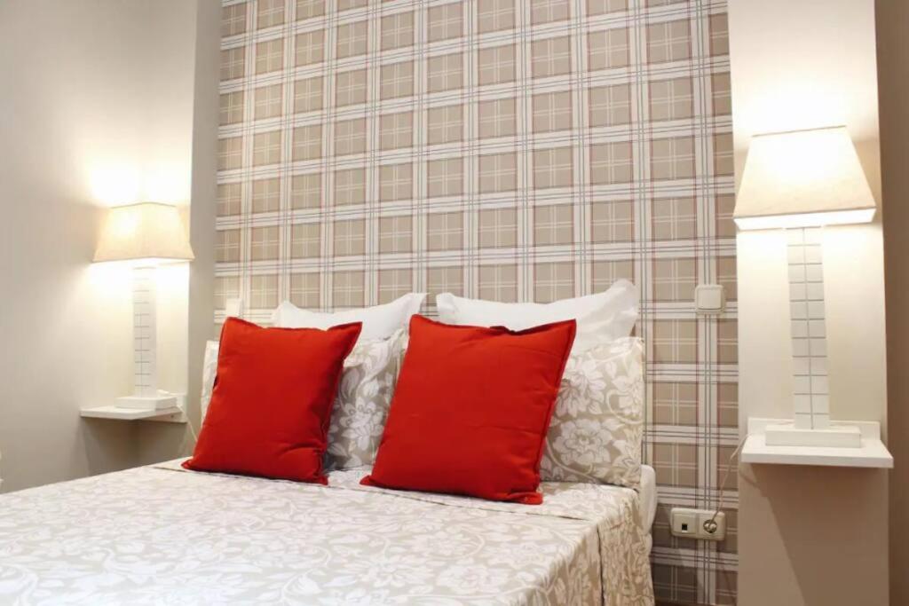 1 dormitorio con 1 cama con almohadas rojas en Acogedor apartamento con acceso directo Plaza Castilla-BULL, en Madrid