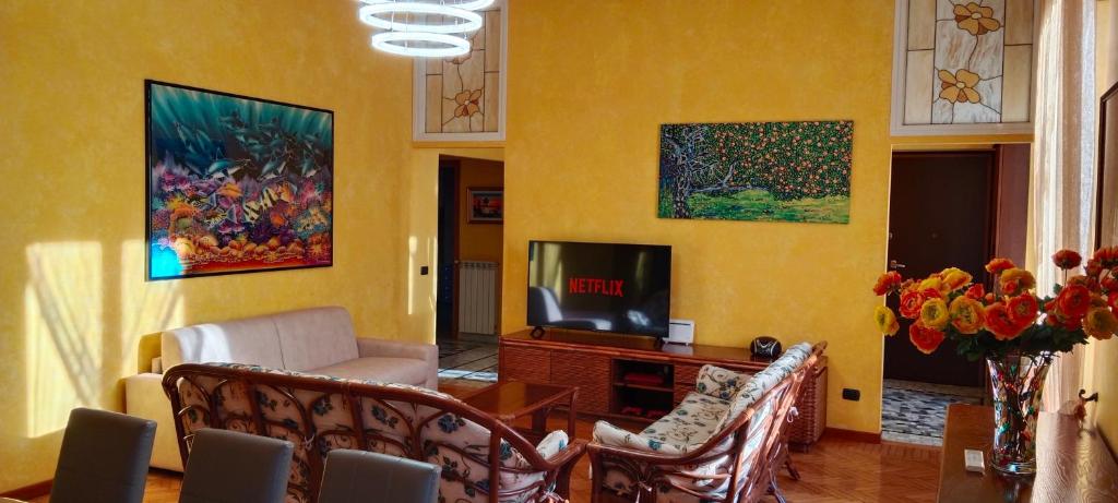 uma sala de estar com televisão, cadeiras e pinturas em Casa vacanze - House Stop and Go em Busto Arsizio