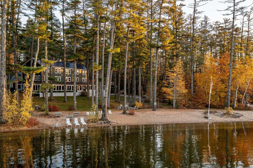 a house in the woods next to a body of water at The Lodge at Pleasant Point in Lovell