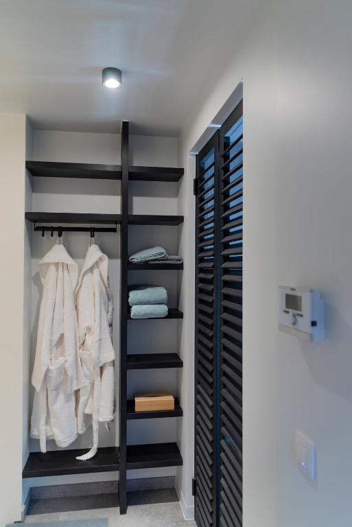 a closet with black shelving and white clothes at De Weldoeninge in Wingene