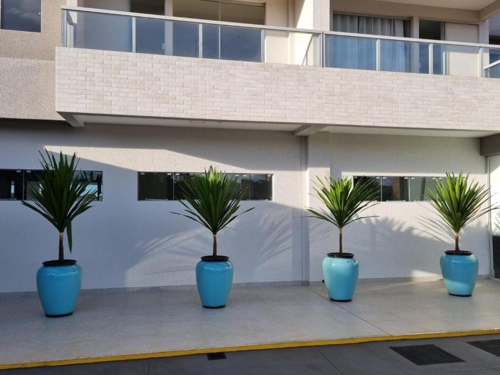 trois pots bleus avec palmiers devant un bâtiment dans l'établissement Condomínio Recanto do Bosque - RBF-09, à Caldas Novas