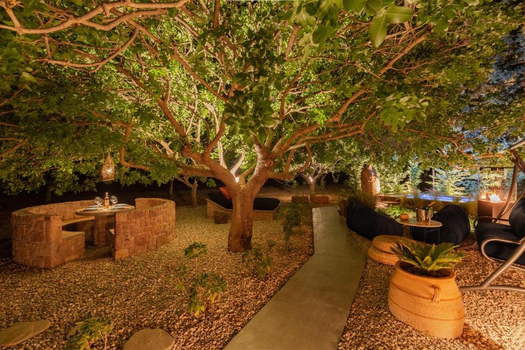 een tuin met een boom en een tafel en stoelen bij Los Pistachios in Aegina Town