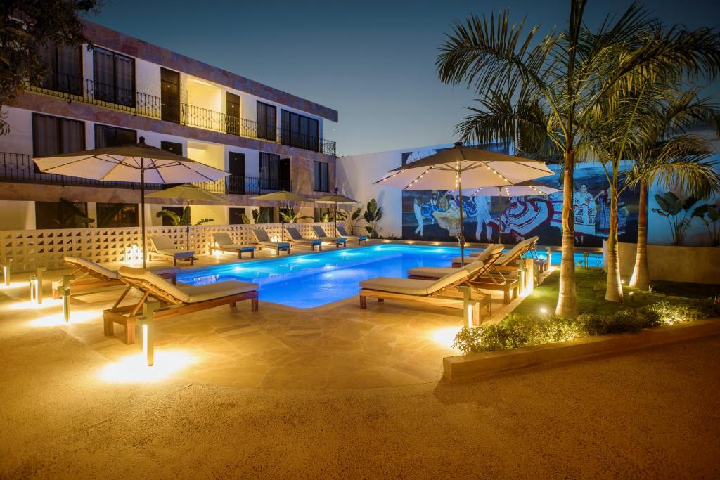 una piscina con sillas y sombrillas junto a un edificio en Hotel Camino Del Sol, en Puerto Escondido