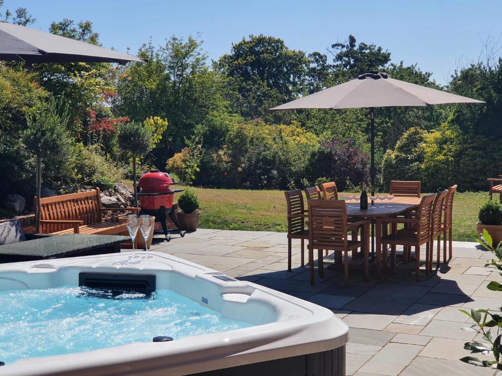 a hot tub with a table and chairs and an umbrella at Luxurious & Modern Large 5 Bed House, HotTub, Views! in Maidstone