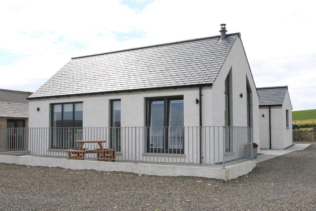 a small white cottage with a fence in front of it at Congesquoy Barn in Stromness