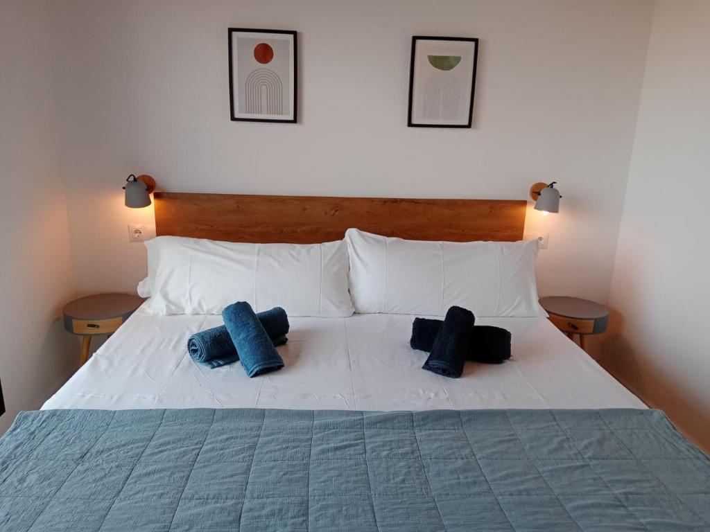 a white bed with two blue pillows on it at CAN LLAVI - TARTANA in Canet de Mar