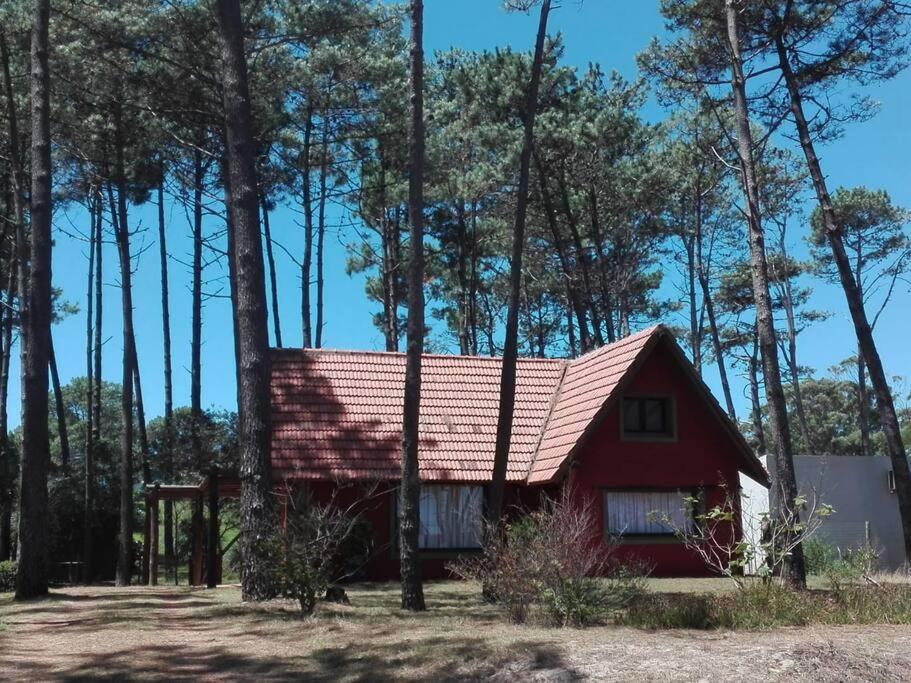 una casa roja con techo rojo en el bosque en Casa En Punta Ballena Zona Chihuahua Mínimo tres noches en Punta del Este