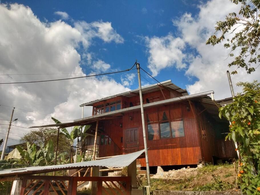 une maison en bois sur le flanc d'une colline dans l'établissement Casa en el rincon familiar en Mindo, à Mindo