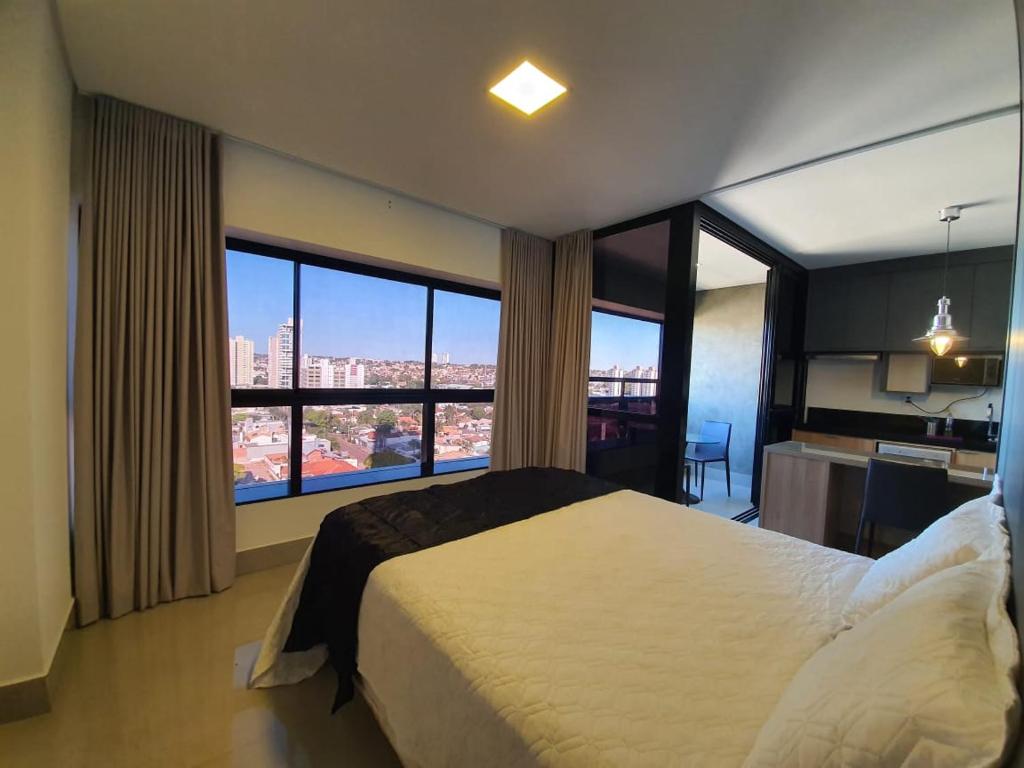 a bedroom with a large bed and large windows at Estúdio Confortável no 12º Andar do Ed. Vertigo in Campo Grande