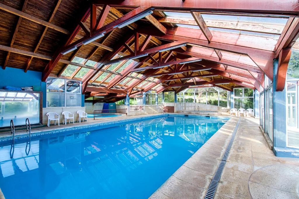 an indoor swimming pool with awning and blue water at Rupu Pehuen Resort in San Carlos de Bariloche