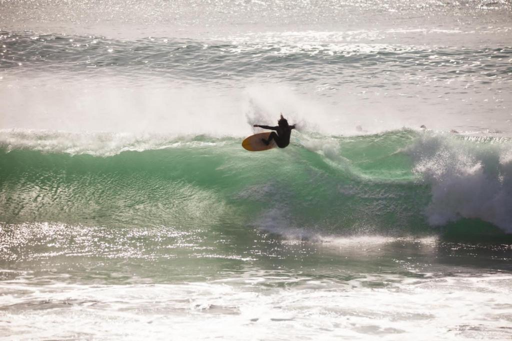 Eine Person, die eine Welle auf einem Surfbrett im Ozean reitet in der Unterkunft Boilers Surf House in Tamri