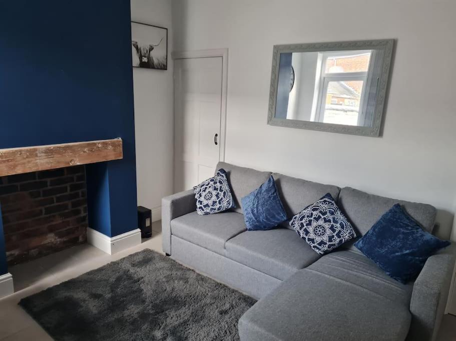 uma sala de estar com um sofá cinzento e almofadas azuis em Primrose Stays - 3 bedroom House em Stoke-on-Trent