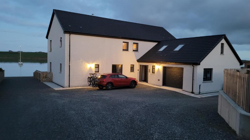 una casa con una macchina rossa parcheggiata di fronte di VitaVer, B&B, STL-OR00012F a Orkney