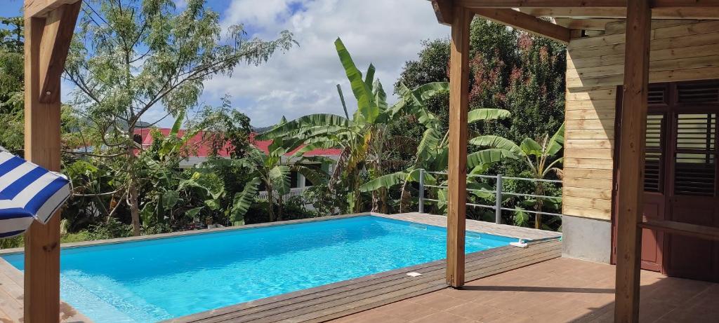 a swimming pool in a backyard with a wooden deck at Noukatchimbe Bungalow avec piscine partagée pour 2 à 4 personnes in Le Marin