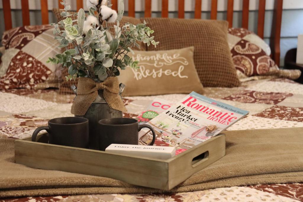 a tray with two cups and a book on a bed at Acorn Hideaways Canton Sweet Dreams for 2 in Canton