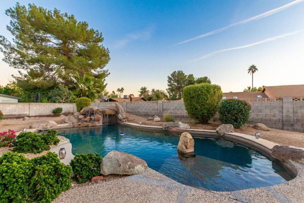 a swimming pool in a yard with rocks and trees at Kathleen House home in Phoenix