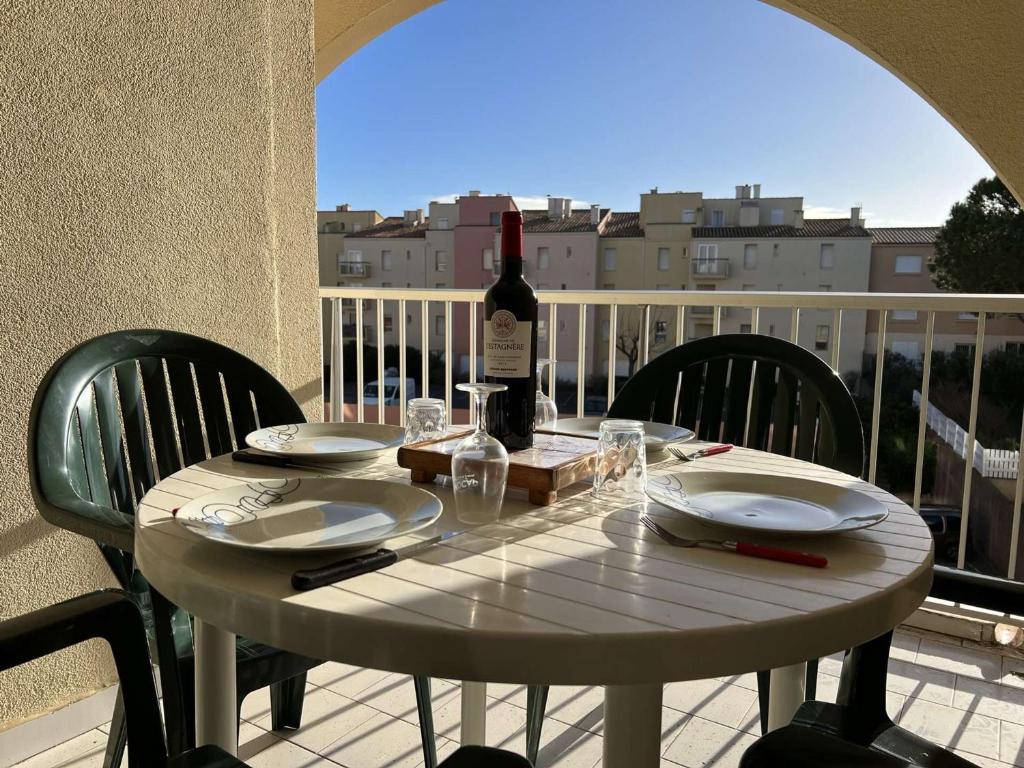 - une table blanche avec une bouteille de vin sur le balcon dans l'établissement Appartement Cap d'Agde, 2 pièces, 6 personnes - FR-1-702-36, au Cap d'Agde