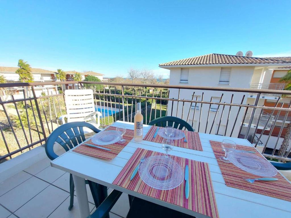 stół z talerzami i przyborami kuchennymi na balkonie w obiekcie Appartement 2 pièces avec accès direct plage, piscine et terrasse - Marseillan - FR-1-326-778 w mieście Marseillan