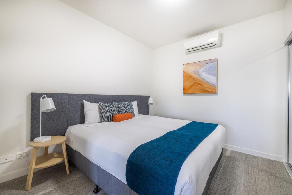 a bedroom with a bed with a blue and white blanket at Aligned Corporate Residences Mackay in Mackay