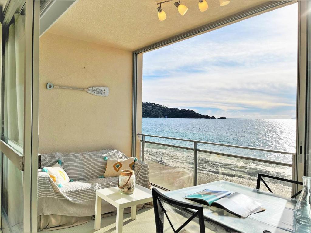 d'un balcon avec un canapé et une table offrant une vue sur l'eau. dans l'établissement Appartement en bord de mer 2 pièces - 5 couchages - Le Lavandou - FR-1-251-430, au Lavandou