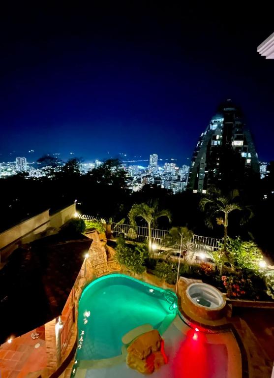 a swimming pool at night with a city in the background at Serenity Suites Casa Boutique in Bucaramanga