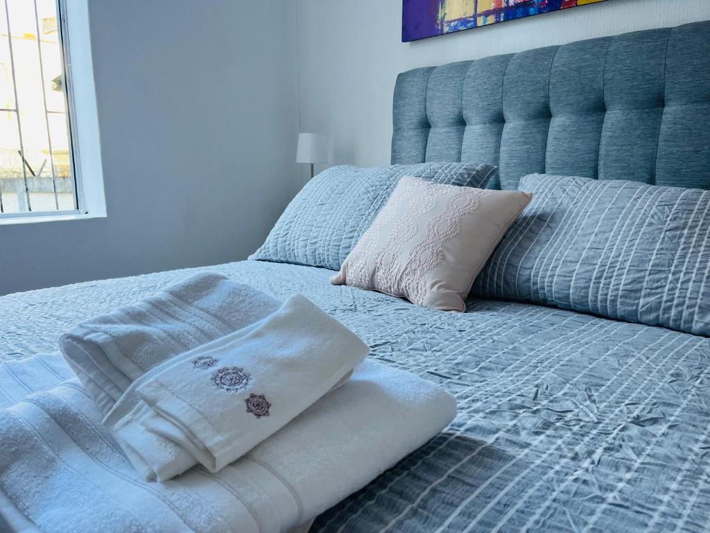 Una cama azul con dos almohadas encima. en Nomada 870 - Hotel Work en Osorno