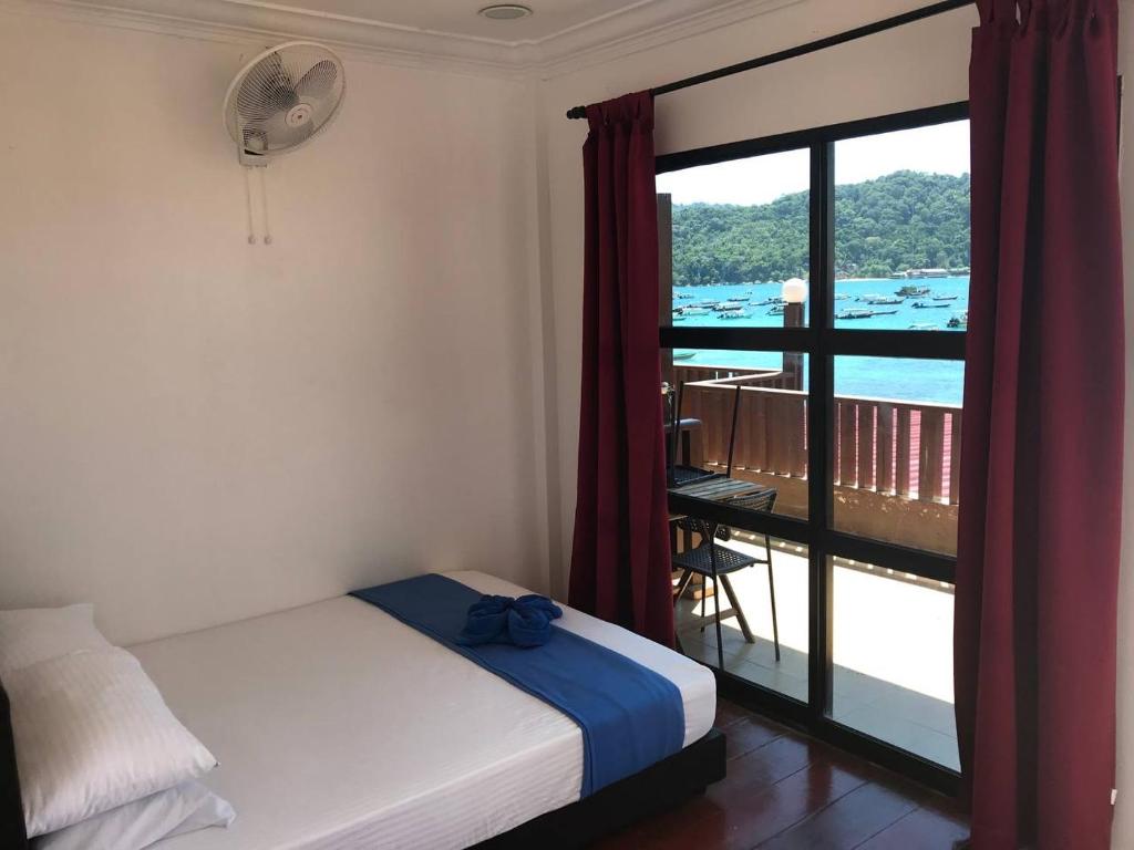 Schlafzimmer mit einem Bett und Blick auf einen Balkon in der Unterkunft Perhentian Nemo Chalet in Perhentian Island