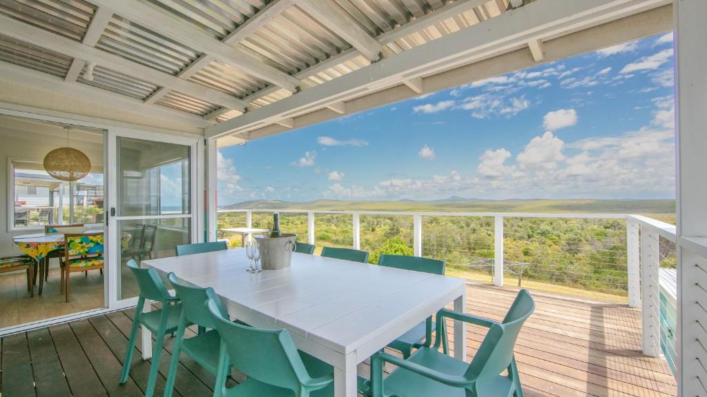 a dining room with a white table and chairs on a deck at Dilkara in Yamba