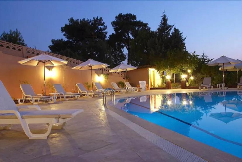 a swimming pool with chairs and umbrellas at night at Boncuklu Otel in Fethiye