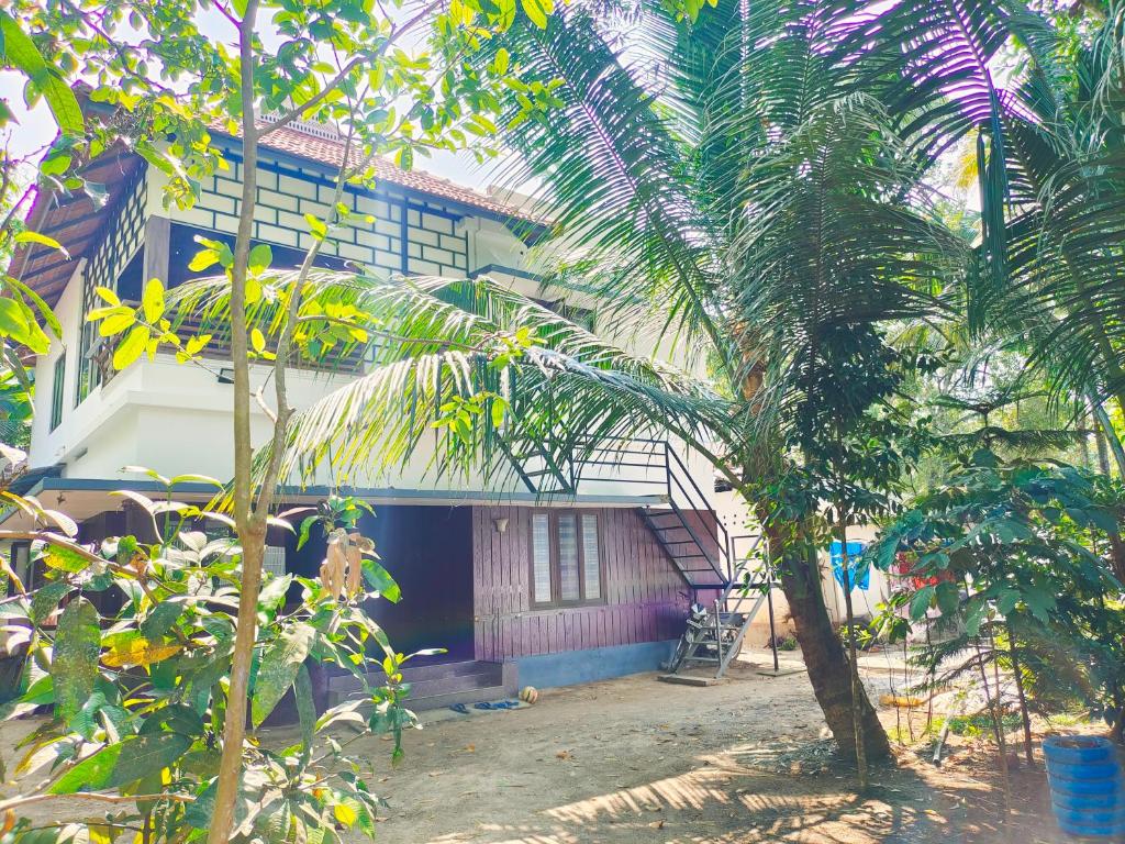 a house with a palm tree in front of it at MARARI CASA LINDA HOMESTAY in Mararikulam