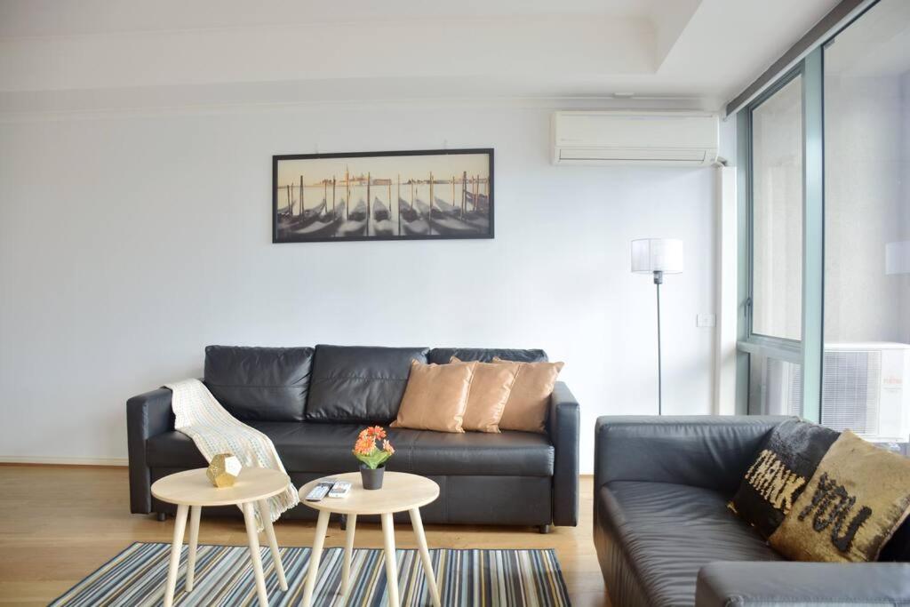 Una sala de estar con un sofá de cuero negro y una mesa. en RiverView Spacious 3BR2Bath2Car WifiPoolGym Crown, en Melbourne