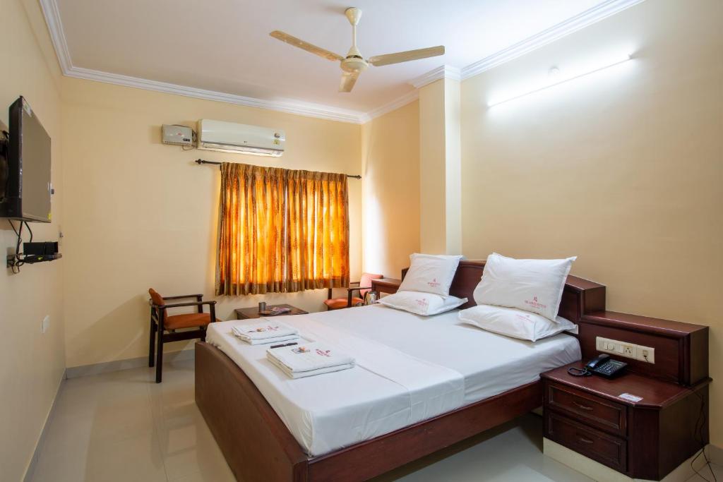 a bedroom with a large bed and a window at Sri Aarvee Hotels in Coimbatore