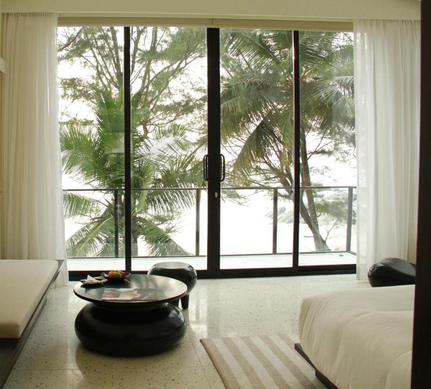 - une chambre avec un lit, une table et une grande fenêtre dans l'établissement The Postcard on the Arabian Sea, à Udupi