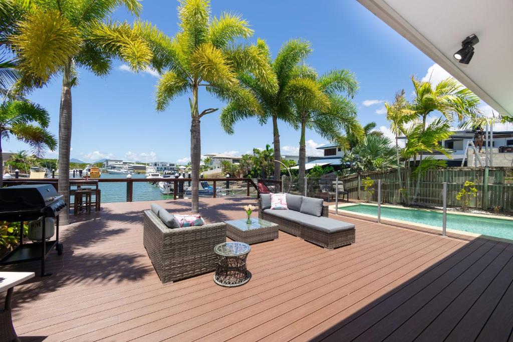 una terraza con palmeras y sofás y una piscina en Cairns Beaches Home, Marina View, Sleeps 12 en Yorkeys Knob