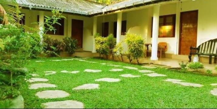 a yard with rocks in front of a house at Green Parrot Family Resort in Polonnaruwa