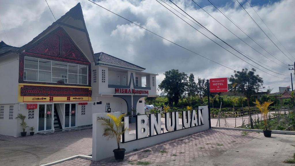 a white building with a sign in front of it at Hotel Wisma Mangurna in Doloksanggul