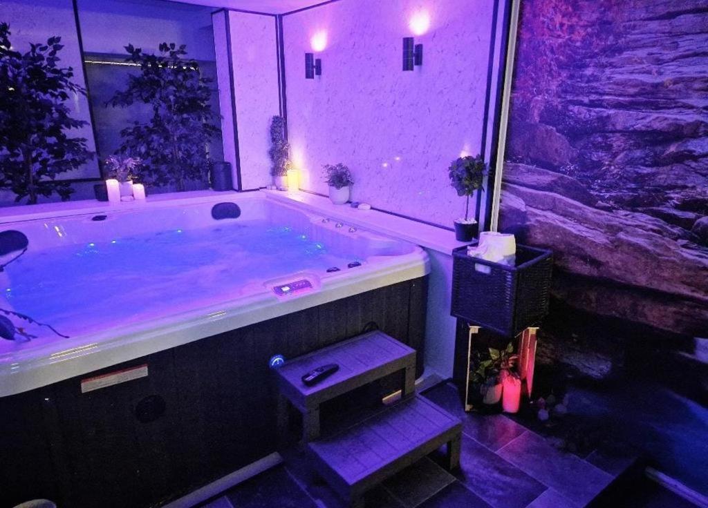 ein Badezimmer mit einer großen Badewanne mit violetter Beleuchtung in der Unterkunft Luxury 9ine SUPER BEAUTIFUL JACUZZI APARTMENT WITH BALCONY in Birmingham
