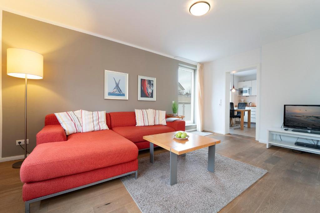 un soggiorno con divano rosso e tavolo di Haus Seestern Seestern 3 a Scharbeutz
