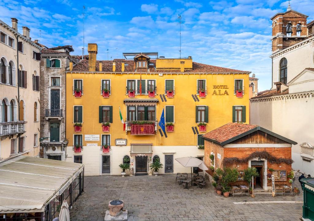 un grand bâtiment jaune au milieu d'une rue dans l'établissement UNAHOTELS Ala Venezia-Adults 16, à Venise