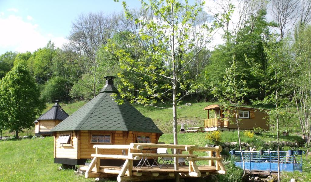 a log cabin in a field with a house at Le Domaine du Châtelet in Ferdrupt