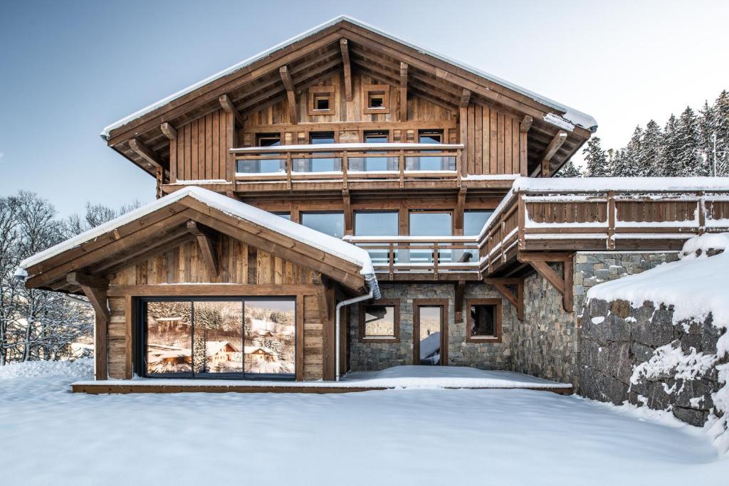 una cabaña de madera en la nieve cubierta de nieve en Le Grand V, chalet de luxe avec piscine intérieure, en Ban-sur-Meurthe-Clefcy