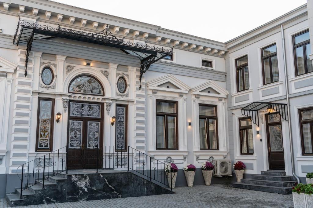 ein großes weißes Gebäude mit einer Treppe und einer Tür in der Unterkunft SIR LUXURY BOUTIQUE HOTEL in Brăila