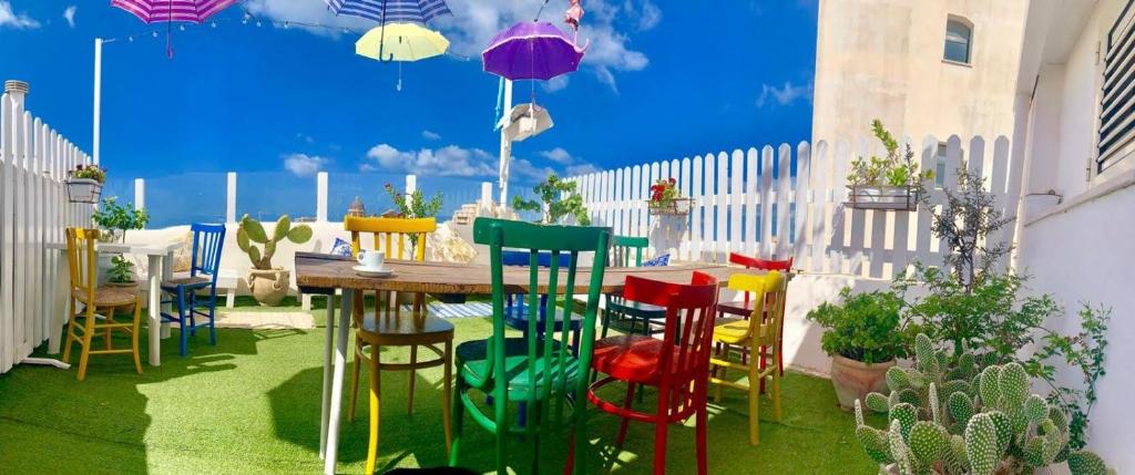 d'une terrasse avec des chaises colorées et une table en bois. dans l'établissement Due Passi Dal Centro, à Marsala