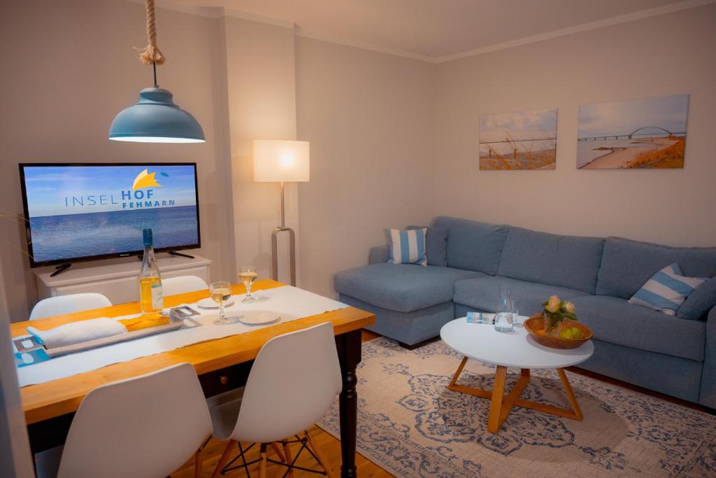 a living room with a blue couch and a table at Seewind - a15221 in Westermarkelsdorf