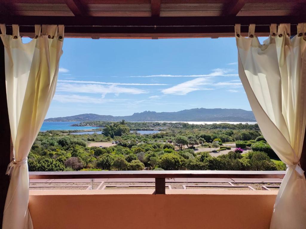 uma janela com vista para o mar e para as montanhas em La Mitica 99 del Portolaconia Residence em Cannigione