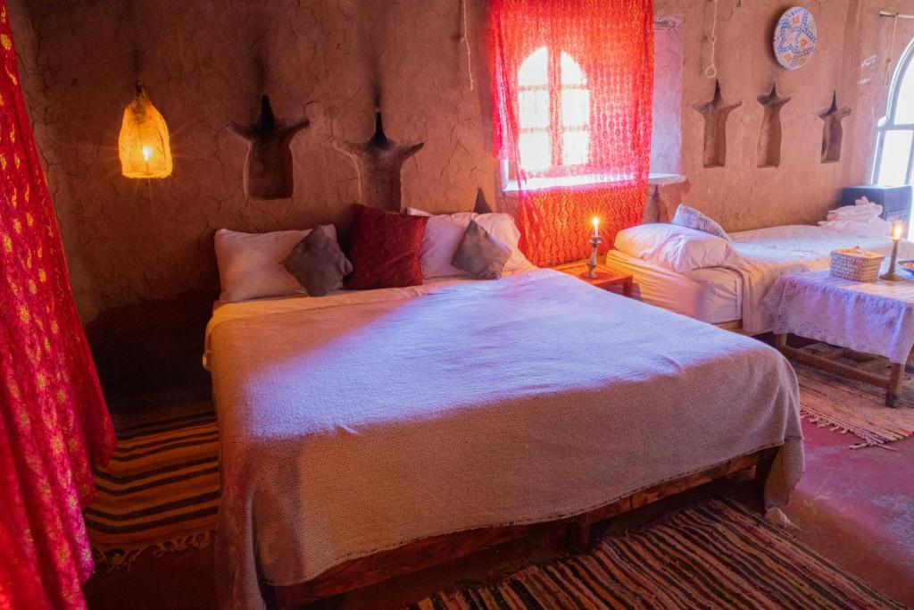 a bedroom with a large bed with red curtains at Kasbah Tebi in Aït Ben Haddou