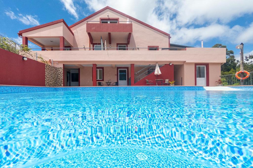 a house with a swimming pool in front of a house at Spacious House with Pool in Prazeres in Prazeres