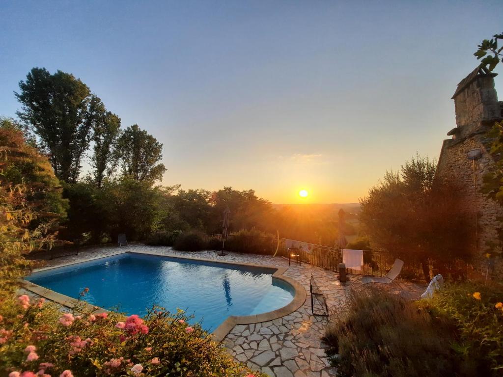 uma piscina num quintal com um pôr-do-sol ao fundo em Lou Cantou em Marnac