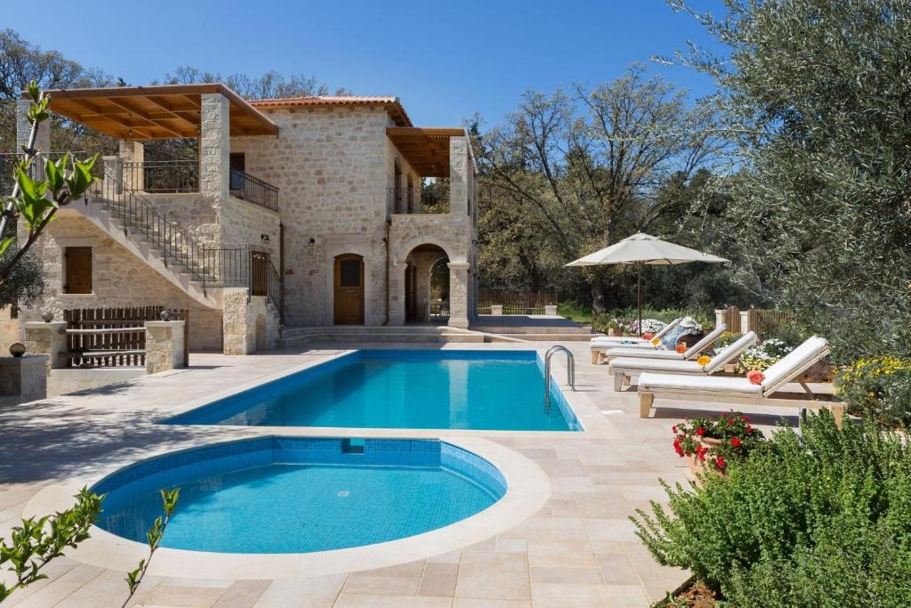 une maison avec une piscine en face d'une maison dans l'établissement Luxury Crete Villa Villa Melpomeni Private Pool Private Playground 5 BDR Rethymno, à Vederoi